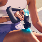 Woman uses Therabody Theragun Pro Plus with cold attachment on her knee accompanied by blue graphic to display its cooling ability