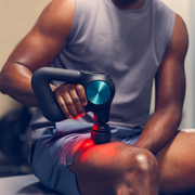 Man using Therabody Theragun Pro Plus to deliver percussive massage and red light therapy to his thigh