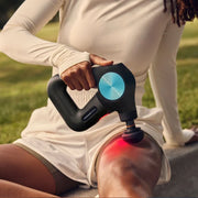 Woman using the Therabody Theragun Pro Plus with the heated percussive attachment on her thigh