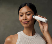 Woman using the Therabody TheraFace Depuffing Wand in white on her cheekbones
