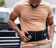 Man adjusting the controls of the Therabody Thermback LED that he is wearing