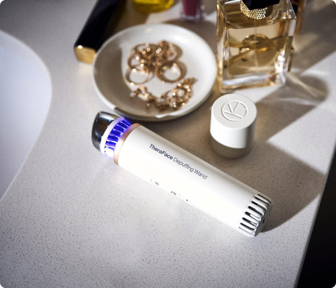 White Therabody TheraFace Depuffing Wand on a vanity table