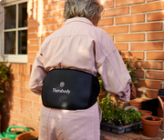 Elderly woman using the Therabody ThermBack LED while gardening 