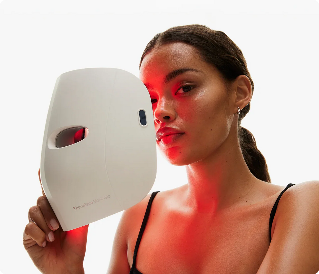 Woman holding Therabody Face Mask Glo with red light therapy activated