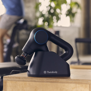 Therabody Theragun Prime Plus in charging stand on a table