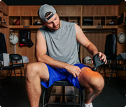 A man delivering heated percussive massage to his thigh with graphics displaying the heat and massage intensity