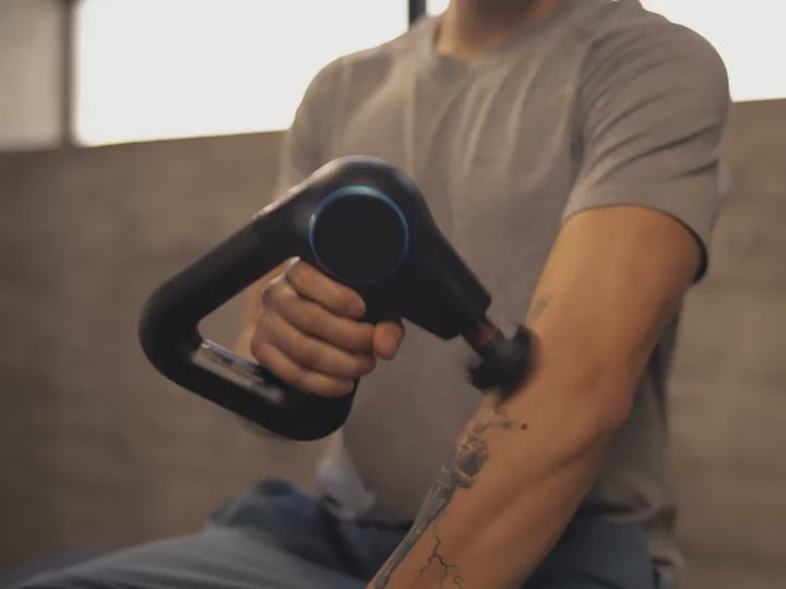Man uses Therabody Theragun Prime fitted with the heated percussive attachment on various parts of his body